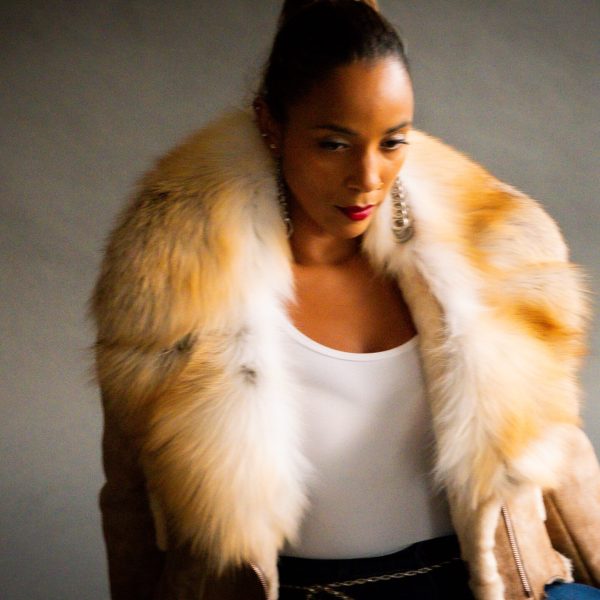 Model wearing blue jeans, white tee and tan leather coat.