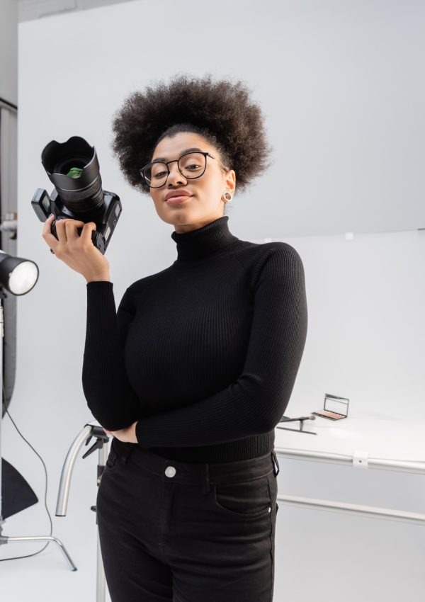 positive african american content maker in black turtleneck and eyeglasses standing with